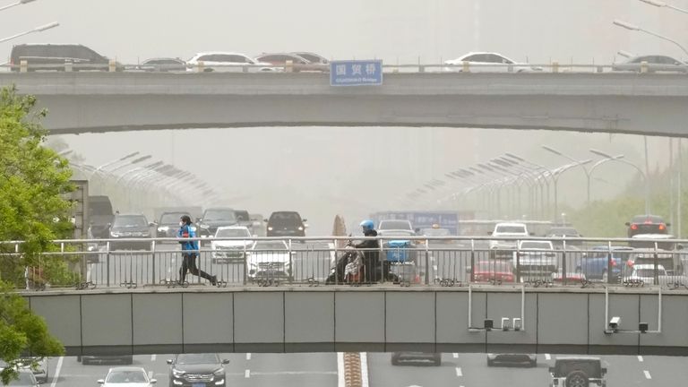 Delivery riders cross a pedestrian bridge over an expressway during...