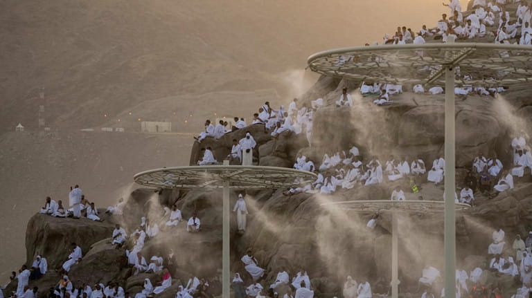 Water mist is sprayed on Muslim pilgrims as they pray...
