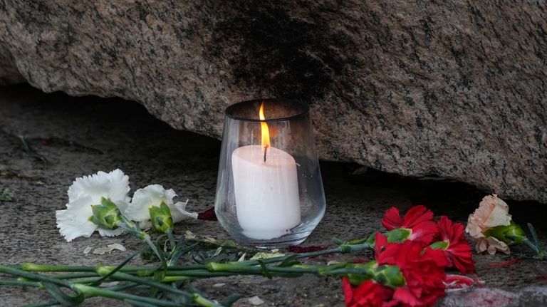 A candle and flower are placed to pay tribute to...