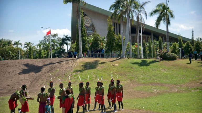 Performers in traditional dresses stand outside of Parliament Haus in...