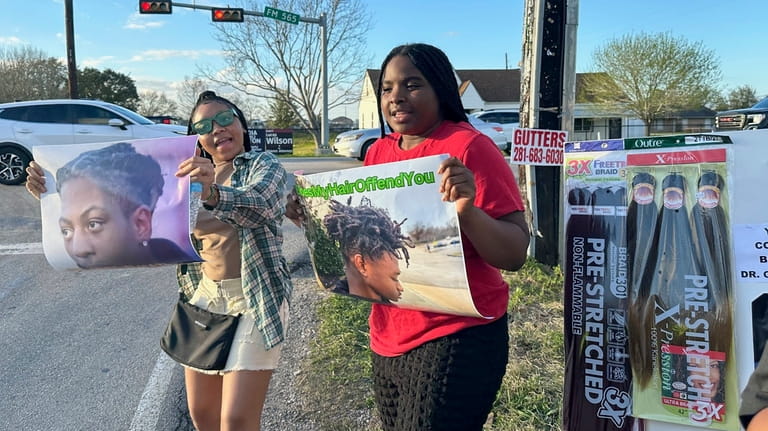 Shan'Terrius Sly-Brown, 16, left, and Shaniya Wade-Red, 15, hold signs...