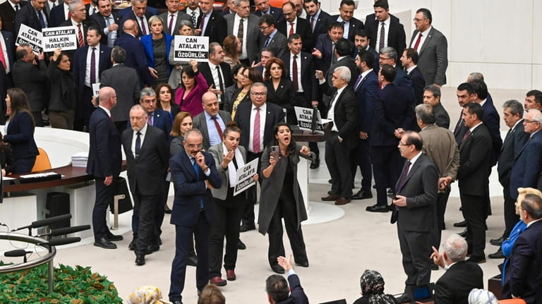 Turkish lawmakers, few holding up boards that read in Turkish:...