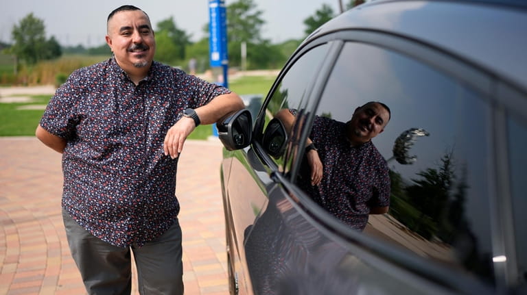 Jose Valdez, 45, who owns three EVs, poses with his...