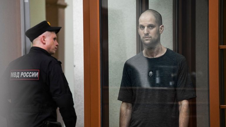 Wall Street Journal reporter Evan Gershkovich stands listening to the...