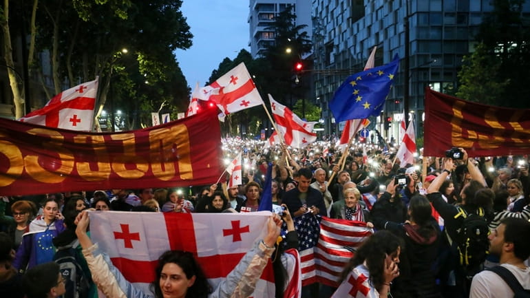 Demonstrators with Georgian national, U.S. and EU flags rally during...