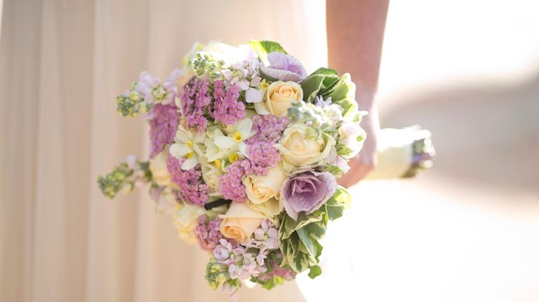 A bride holds a bouquet during her wedding in Ein...