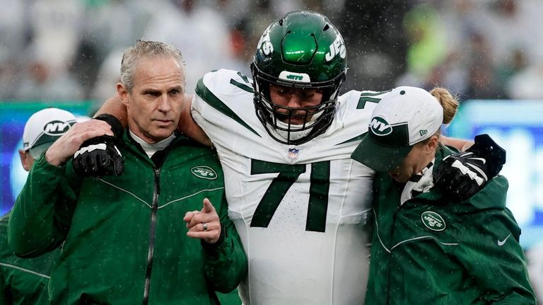 Wes Schweitzer #71 of the New York Jets is helped...