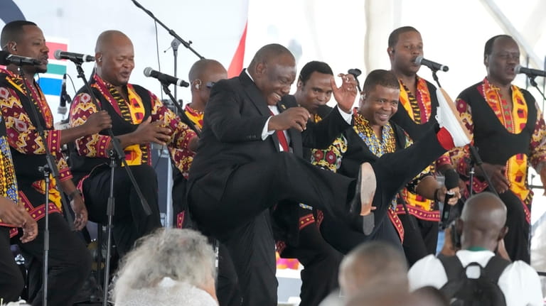 South African President Cyril Ramaphosa, centre, dances to music as...