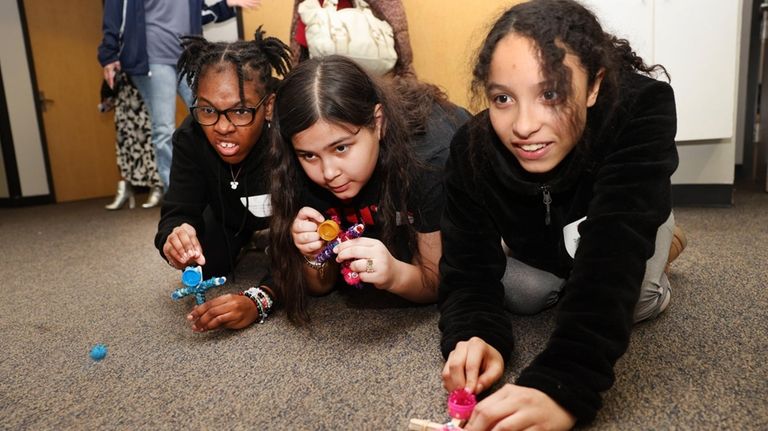 Girls use catapults they made using popsicle sticks to hit...