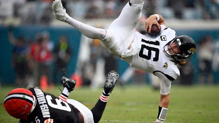 Jacksonville Jaguars quarterback Trevor Lawrence (16) leaps over Cleveland Browns...