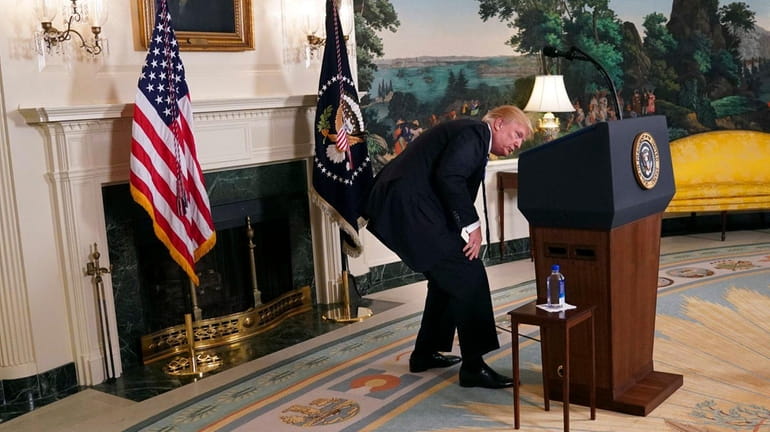 President Donald Trump looks for his water bottle as he...