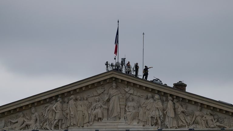 Security staff stand atop the roof of the National Assembly...