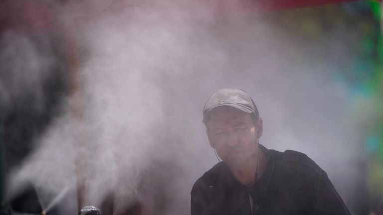 A person cools off in a mister along the Las...