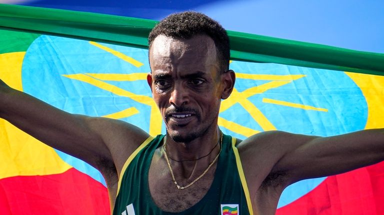 Ethiopia's Tamirat Tola celebrates after crossing the finish line to...