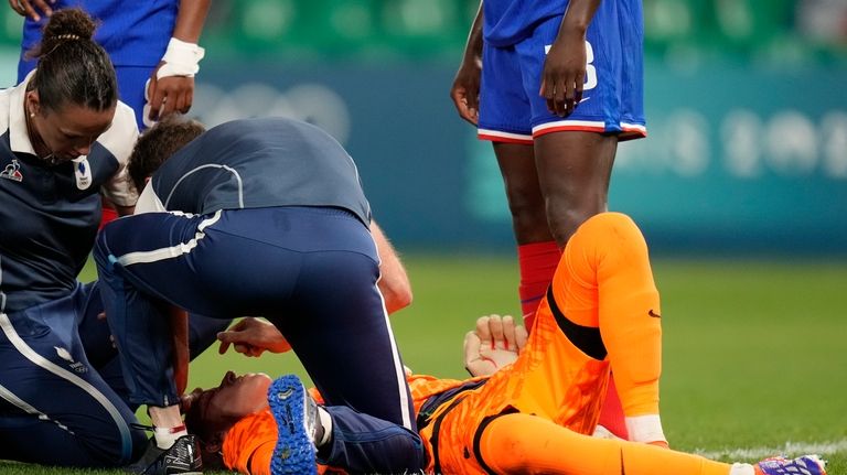 France's goalkeeper Pauline Peyraud-Magnin gets assistance before being carried off...