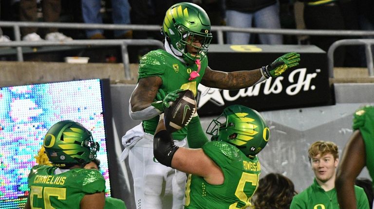 Oregon running back Bucky Irving is hoisted by Oregon offensive...