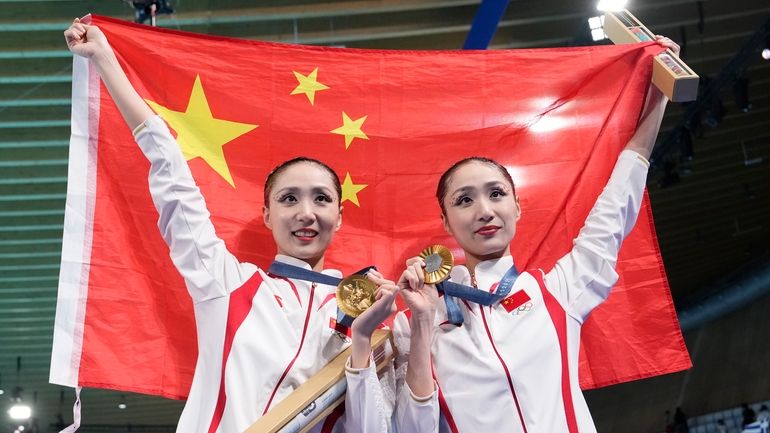 China's Wang Liuyi and Wang Qianyi, hold their national flag...