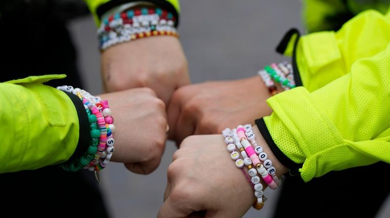 Four police officers show their wrist bands that have names...