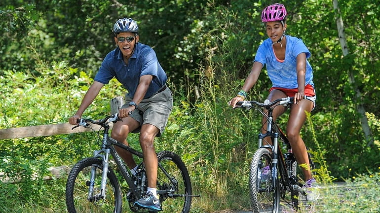 President Barack Obama and his daughter, Malia, ride a bike...