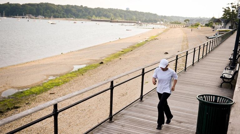 A woman runs on the boardwalk of Sea Cliff Beach.