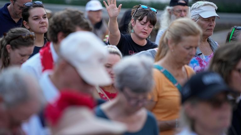 Shelby Slowey raises her hand during a prayer session before...