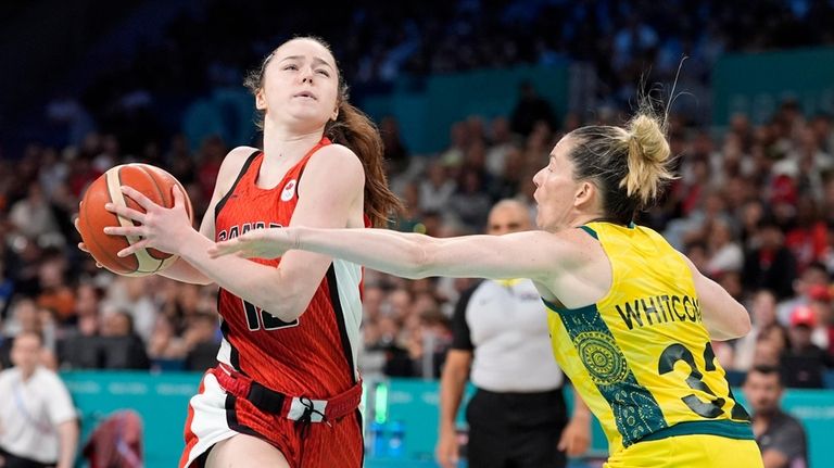 Canada's Syla Swords, left, drives toward the basket as Australia's...