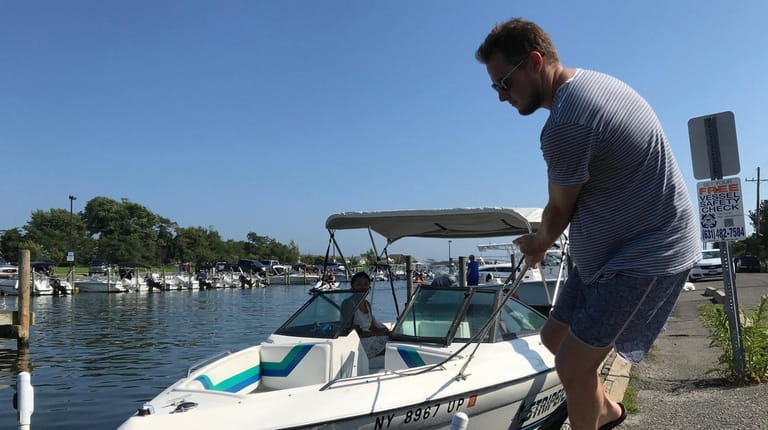 Kyle Estelle pulls in a boat with Evalise Salas, left,...