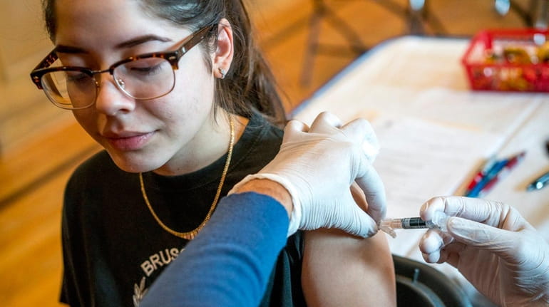 Pharmacist Gregory Lachhman administers a flu shot to Lily Parra,...