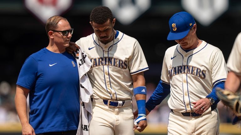 Seattle Mariners centerfielder Julio Rodriguez, center, is helped from the...