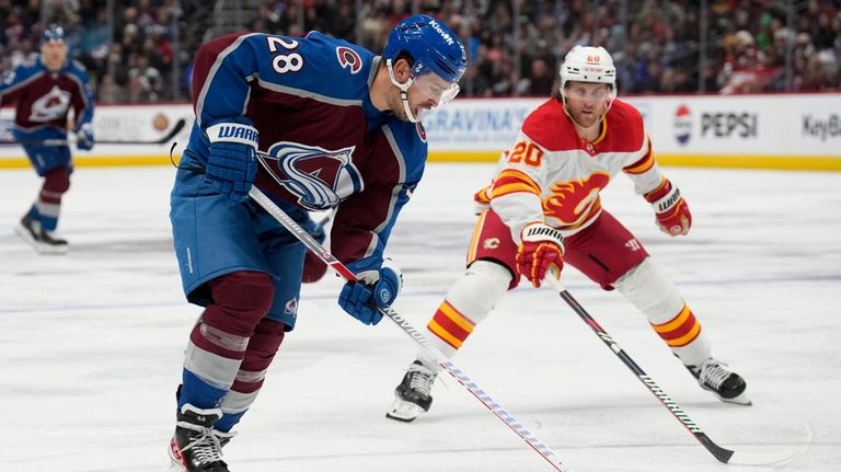 Colorado Avalanche left wing Miles Wood, left, moves the puck...