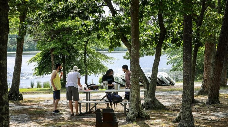 A group of friends gather at a picnic bench overlooking...