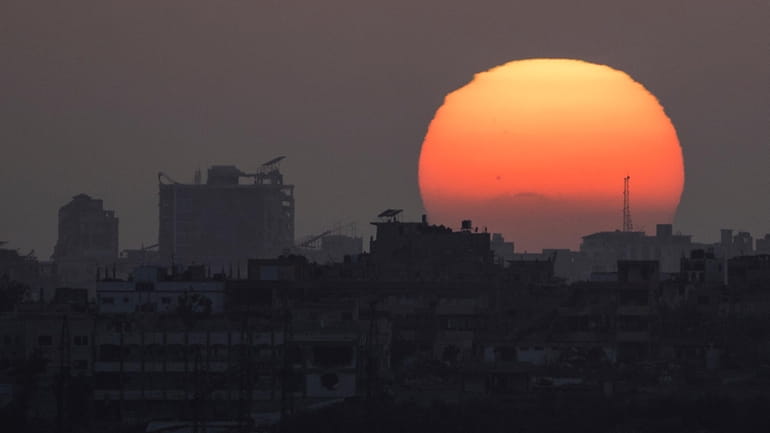 The sun sets behind the buildings in the Gaza Strip...