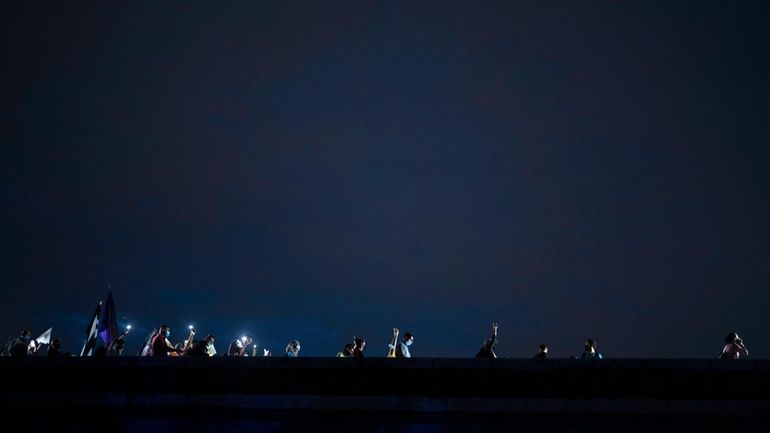 People march along Las Americas Highway to protest the LUMA...