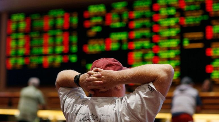 A man watches a baseball game in the sports book...