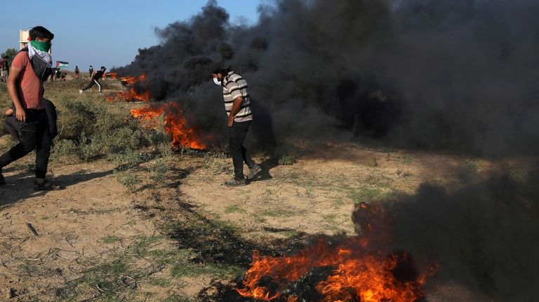 Palestinian protesters burn tires during clashes with Israeli security forces...