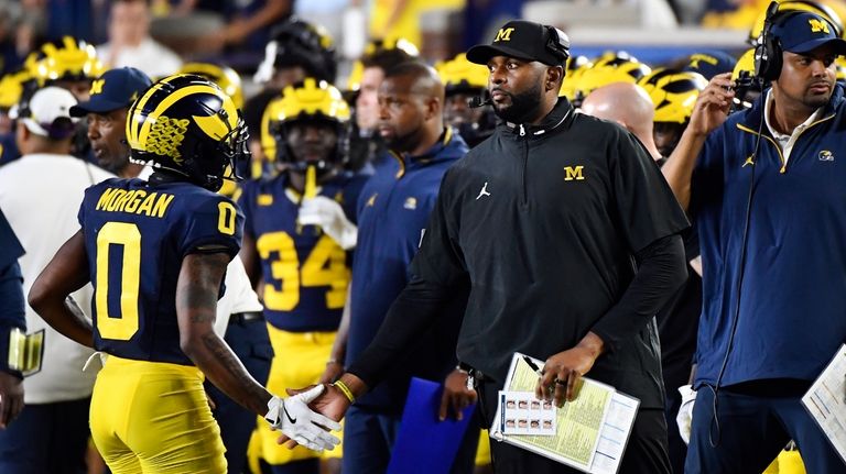 Michigan head coach Sherrone Moore, second from right, congratulates wide...