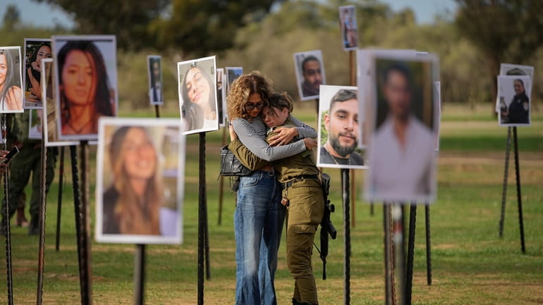 Israelis embrace next to photos of people killed and taken...