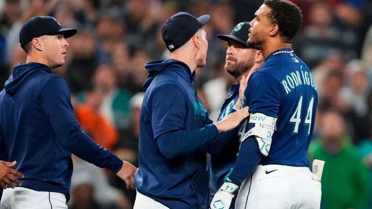 Seattle Mariners' Julio Rodriguez (44) is held back by teammate...