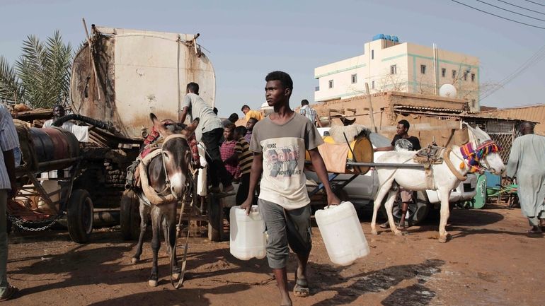 People gather to collect water in Khartoum, Sudan, on May...