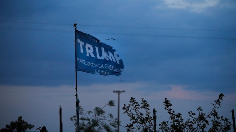 A withered Donald Trump campaign flag stands on a field.