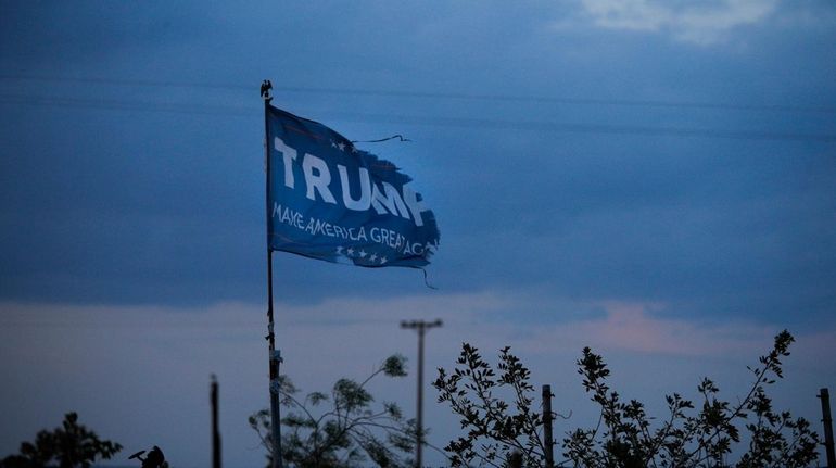 A withered Donald Trump campaign flag stands on a field.