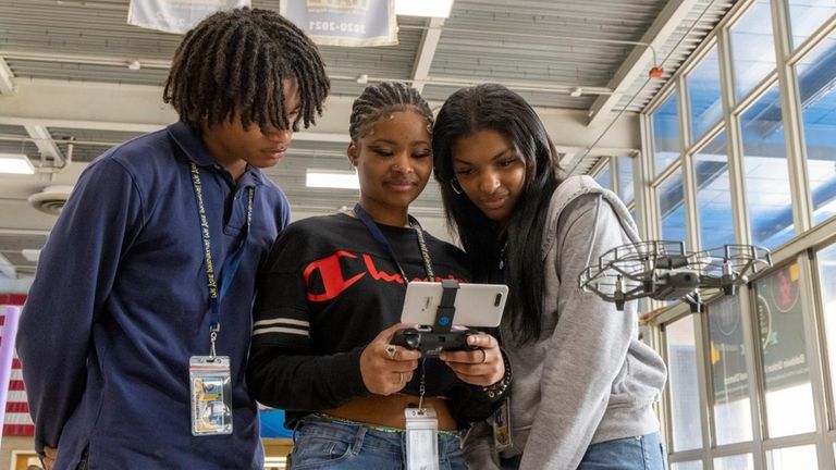 Students Frantz Byron, left, Nichealla Fong-Woo and Amonni Forde fly a drone...