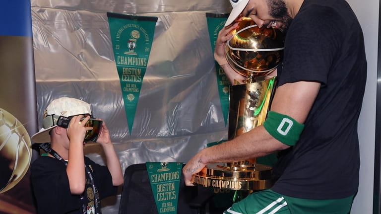 Boston Celtics forward Jayson Tatum embraces the Larry O'Brien Championship...