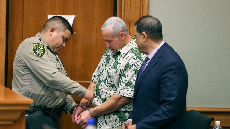 A court officer removes Albert "Ian" Schweitzer's handcuffs following the...