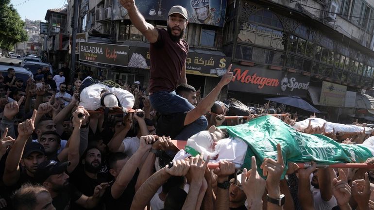 Mourners carry the bodies of five Palestinians during their funeral,...