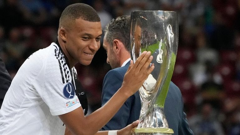 Real Madrid's Kylian Mbappe touches the trophy during the medal...