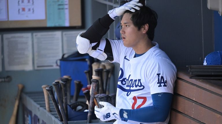 Los Angeles Dodgers' Shohei Ohtani gets ready in the dugout...