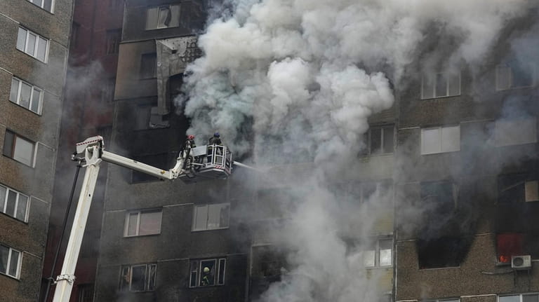 Firefighters work to extinguish a fire in an apartment building...