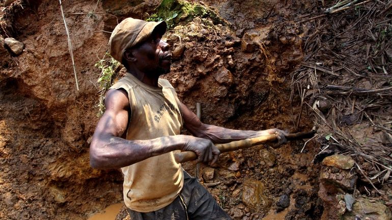 One of the few remaining miners digs out soil which...