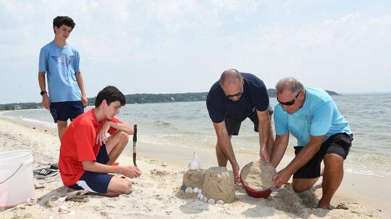 Brothers Tyler and Jacob Malkush, 15, watch as their father,...